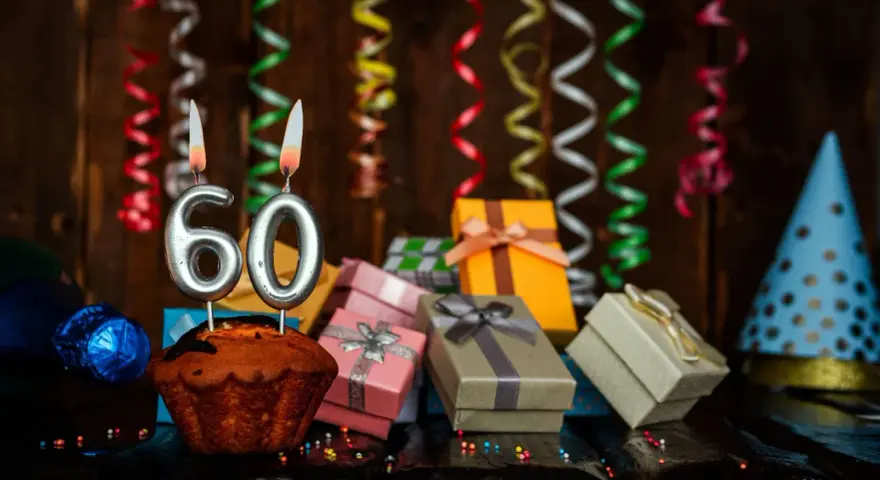 Urodzinowy muffin z cyframi 60, prezentami i serpentynami. Idealne życzenia na 60 urodziny!