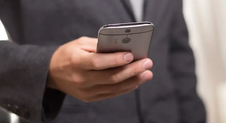 Mężczyzna w garniturze trzyma telefon, zastanawiając się, jak złożyć kondolencje przez telefon.