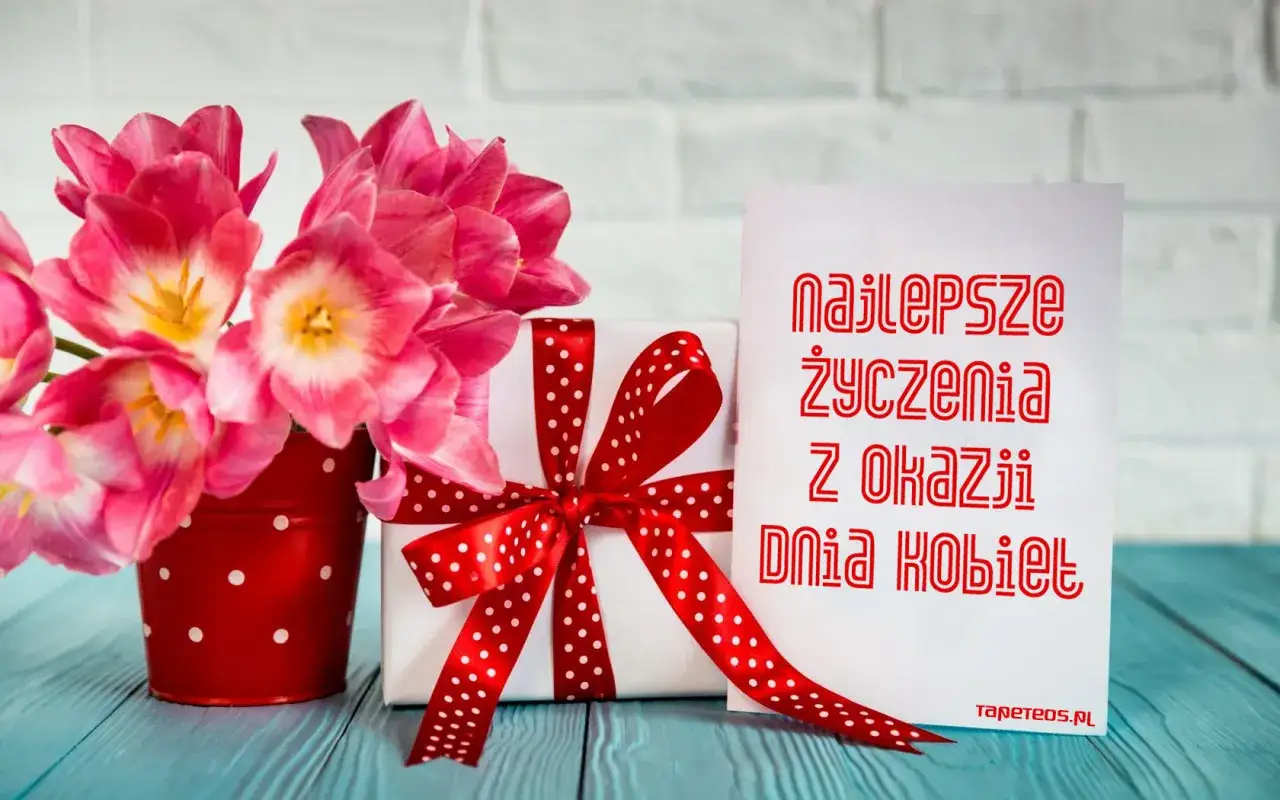 Różowe tulipany w czerwonym, kropkowanym wazonie, biały prezent z czerwoną wstążką i kartka z napisem