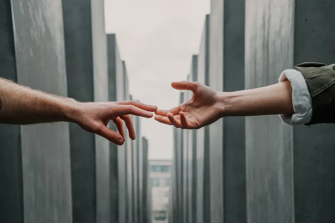 Dwie dłonie zbliżają się do siebie, symbolizując podziękowanie za pomoc i zaangażowanie.
