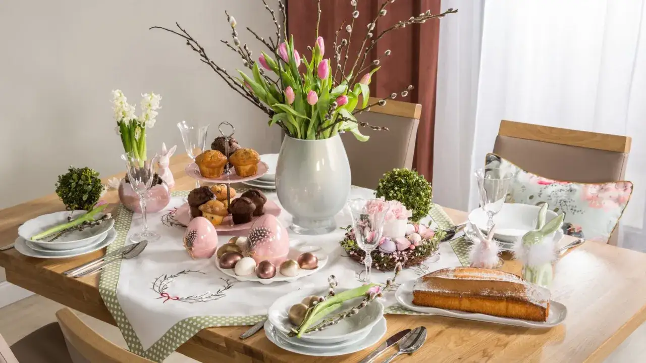Nowoczesny stół wielkanocny: babeczki, pisanki, ciasto i bukiet różowych tulipanów.